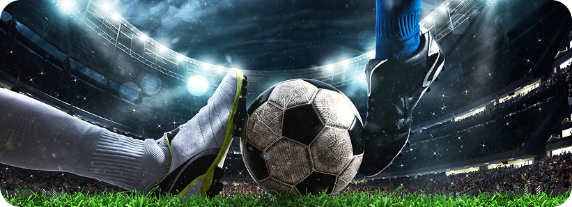 Close-up of two players' boots challenging for a soccer ball on a floodlit stadium pitch at night