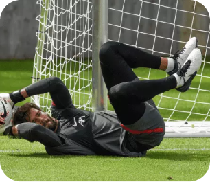 Goalkeeper in all-black kit on the ground making a low save during training