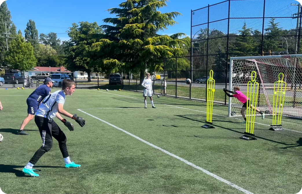 Goalkeeper training session on an outdoor turf field with a coach