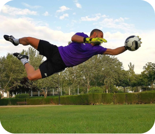 `Goalkeeper in purple kit making a full-stretch diving save during outdoor training`